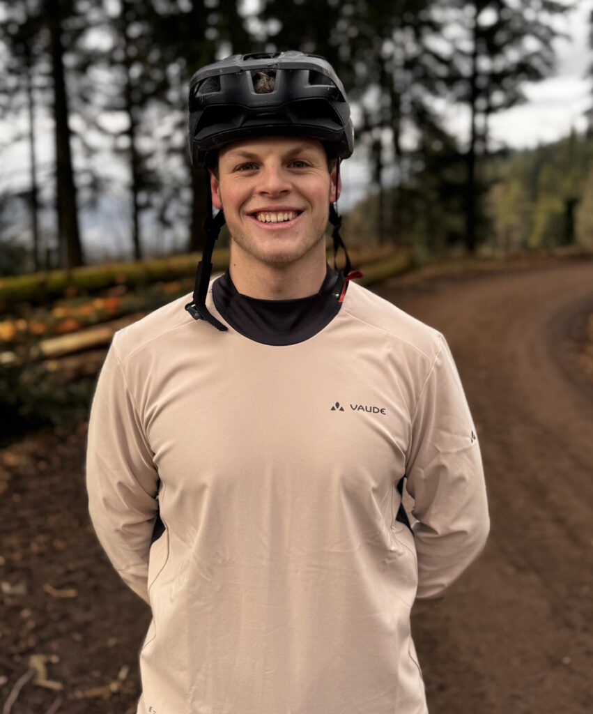 Ein junger Mann in sportlicher Bekleidung mit Helm in einem Waldgebiet