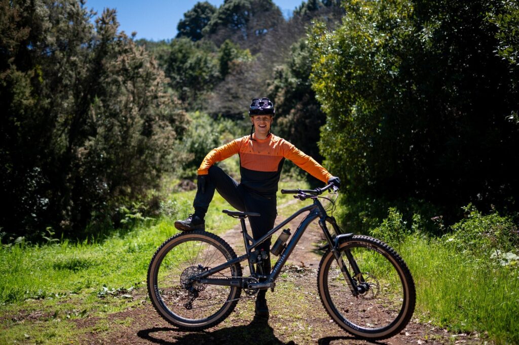 Ein Mountainbiker posiert mit seinem Fahrrad auf einem Waldweg.