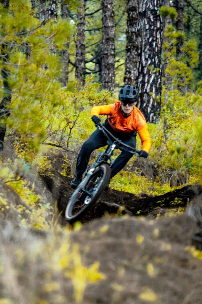 Ein Mountainbiker fährt auf einem schmalen Pfad durch einen Wald.